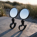 La paire de rétroviseurs ronds FATADDICT, miroirs de 8 cm sur rotule courte et sangle crantée, posés devant les dunes